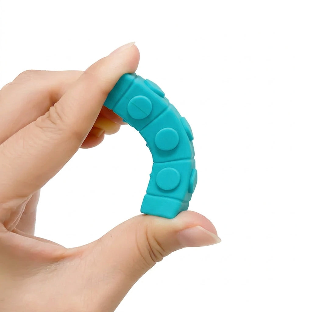A hand holding a bright green, curved silicone finger exerciser with raised circular pads, shown against a plain white background.