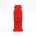 A red robot-shaped silicone synaptoys pen topper with embossed details, standing upright on a light gray background.